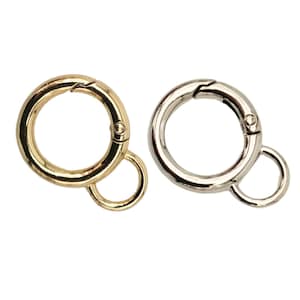 Könnte beinhalten: Zwei Schlüsselringe aus Metall, einer goldfarben und einer silberfarben, mit einem Drehverschluss und einem kleineren Ring.