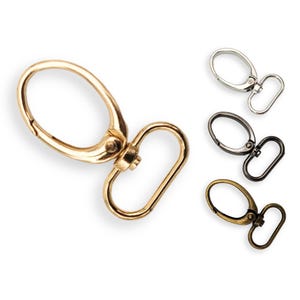 May include: Four swivel snap hooks in different finishes: gold, silver, antique brass, and black nickel. Each hook has a round opening and a rectangular loop.