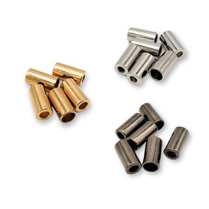 May include: Assortment of metal end caps in gold, silver, and black. The end caps are cylindrical and have a hole in the center. They are used to finish off cords or ropes.