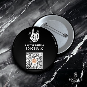 May include: Black button badge with the text "BUY THE BRIDE A DRINK" and a skeleton hand graphic. Includes a QR code with a photo. The badge is round with a metal pin back.