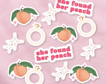 Può includere: Una collezione di adesivi su sfondo rosa. Gli adesivi includono illustrazioni di pesche con foglie verdi, anelli di diamanti, stelle filanti e il testo "she found her peach" in lettere rosa.