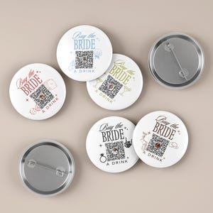 May include: Six round white pin-back buttons featuring the text Buy the Bride a Drink and a central QR code. Each button displays unique icons like dice, seashells, martini glasses, rings, or cowboy hats in blue, red, gold, black, and brown ink.