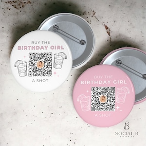 Puede incluir: Dos botones redondos blancos y rosas con el texto "BUY THE BIRTHDAY GIRL A SHOT". Cada botón presenta un código QR y una ilustración de cóctel. Los botones tienen un alfiler plateado en la parte posterior.