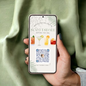 May include: A smartphone displaying a bachelorette party invitation for a Scottsdale event called "Grace's Bachelorette: Scottsdale Before the Veil". The invitation features a QR code with the text "Buy the Bride a Drink" and a graphic of four cocktails.