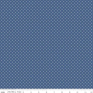May include: A blue fabric featuring a repeating pattern of small white polka dots. A white ruler is visible along the bottom edge, showing a measurement scale from 0 to 12 inches, with the text Riley Blake Designs printed on it.