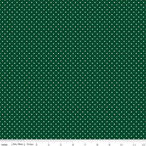 May include: A dark green fabric featuring a repeating pattern of small white polka dots. A white ruler is visible at the bottom edge, showing a scale of 12 inches, with the text Riley Blake Designs printed along the measurement line.