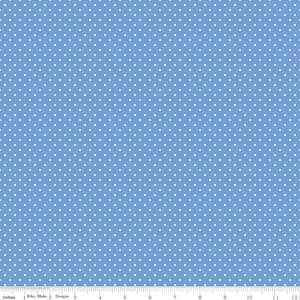 May include: A light blue fabric featuring a repeating pattern of small white polka dots. A white ruler is visible at the bottom edge, showing a scale of 12 inches, with the text Riley Blake Designs printed along the measurement line.