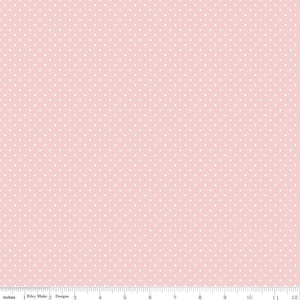 May include: A light pink fabric featuring a repeating pattern of small white polka dots. A white ruler is visible at the bottom edge, showing a scale of 12 inches, with the text Riley Blake Designs printed near the left side.
