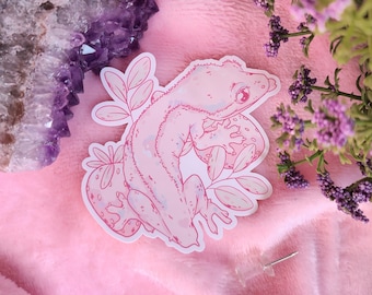 Könnte beinhalten: Rosa-weißer Aufkleber mit einer Strichzeichnung eines Geckos mit floralem Design. Der Gecko ist zusammengerollt, mit dem Schwanz um seinen Körper gewickelt.