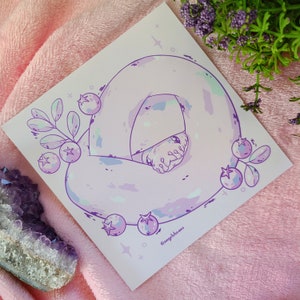 Könnte beinhalten: Eine lila und weiße Illustration einer Schlange, die sich mit Blaubeeren und Blättern zusammengerollt hat. Die Schlange hat einen helllila Körper mit weißen Flecken und einen helllila Kopf. Die Blaubeeren sind hellblau mit weißen Highlights. Die Blätter sind hellgrün mit weißen Highlights. Der Hintergrund ist hellrosa mit weißen Sternen. Der Text "@angyldbeans" befindet sich in der rechten unteren Ecke.