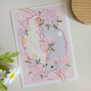 May include: Two white and grey rats with pink flowers and leaves. The rats are curled up together, and the flowers are blooming around them.