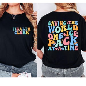 May include: Black t-shirt with the text "HEALTH CLERK" in colorful letters on the front. The back of the shirt features the phrase "SAVING THE WORLD ONE ICE PACK AT A TIME" in a retro font with medical-themed graphics.