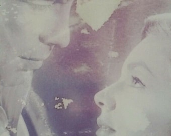 Può includere: Una fotografia vintage di una coppia che si guarda. L'immagine è sbiadita e ha un'atmosfera morbida e romantica.