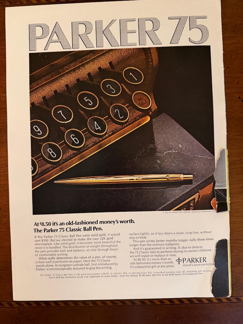 May include: An advertisement for the Parker 75 Classic Ball Pen. The ad features a gold pen on a dark surface, with the headline "PARKER 75." Text describes the pen's features and value. The background includes a vintage typewriter.