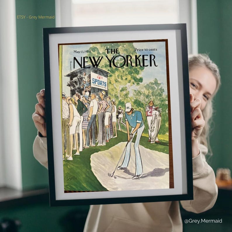 May include: Framed vintage New Yorker magazine cover from May 13, 1974, featuring a golf scene. The artwork depicts a golfer in blue and white striped pants, with spectators in the background. The magazine title and price are visible.