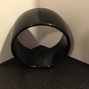 May include: A black, round, plastic bangle bracelet.