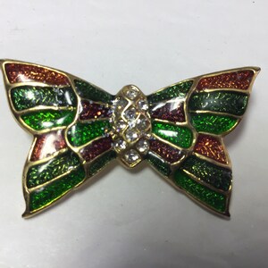 May include: A gold-tone butterfly brooch with green, red, and orange enamel and clear rhinestones.