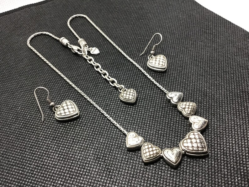 Puede incluir: Un collar de plata con una cadena y cinco colgantes en forma de coraz&oacute;n. El collar se combina con pendientes de coraz&oacute;n de plata a juego.