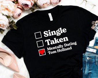 May include: Black t-shirt with a white check box list that reads "Single", "Taken", and "Mentally Dating Tom Holland". The check box next to "Mentally Dating Tom Holland" is checked and has a red heart.