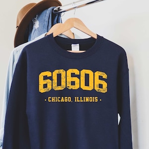 May include: Navy blue sweatshirt with a yellow graphic of the number 60606 and the text "CHICAGO, ILLINOIS".