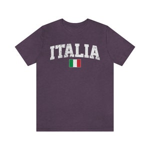 May include: A purple t-shirt with the word "ITALIA" in white with a distressed look and the Italian flag underneath.