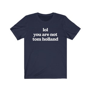 May include: Navy blue t-shirt with white text that reads "lol you are not tom holland".