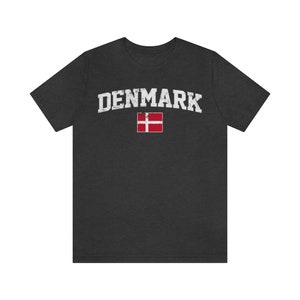 K&ouml;nnte beinhalten: Ein dunkelgraues T-Shirt mit einem wei&szlig;en, abgenutzten Aufdruck des Wortes "DENMARK" und der d&auml;nischen Flagge.