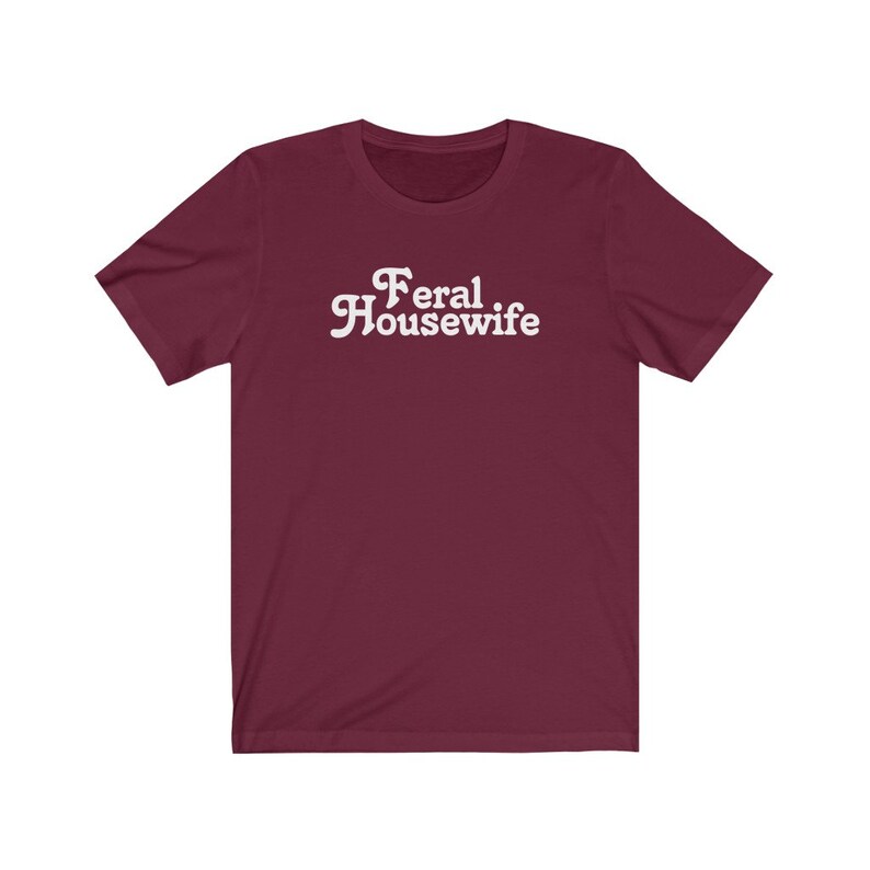 May include: Burgundy short-sleeved t-shirt with white text that reads "Feral Housewife".