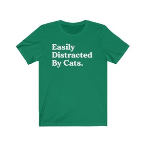 Może przedstawiać: Zielony T-shirt z białym tekstem, kt&oacute;ry brzmi "Easily Distracted By Cats."