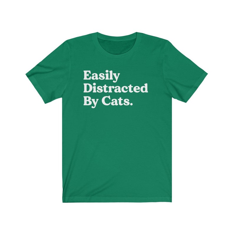 Może przedstawiać: Zielony T-shirt z białym tekstem, kt&oacute;ry brzmi "Easily Distracted By Cats."