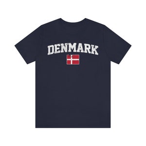 K&ouml;nnte beinhalten: Ein marineblaues T-Shirt mit einem wei&szlig;en, abgenutzten Aufdruck des Wortes "DENMARK" und der d&auml;nischen Flagge.