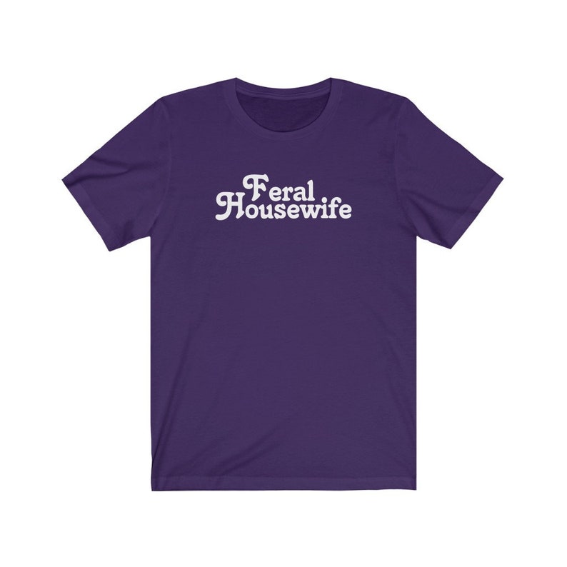 May include: Purple short-sleeved t-shirt with white text that reads "Feral Housewife".