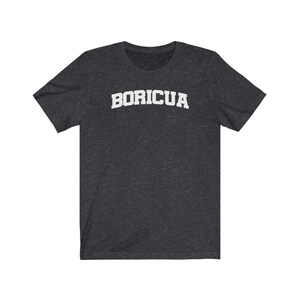 May include: A dark heather grey t-shirt with the word "BORICUA" printed in white on the front.