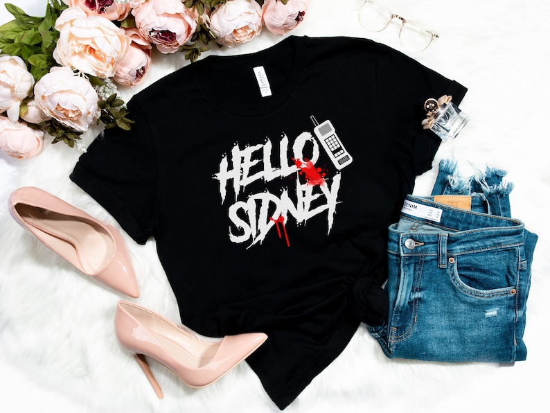 K&ouml;nnte beinhalten: Schwarzes T-Shirt mit einem wei&szlig;en Aufdruck, der "Hello Sidney" mit einem roten Blutspritzer und einem alten Mobiltelefon sagt.