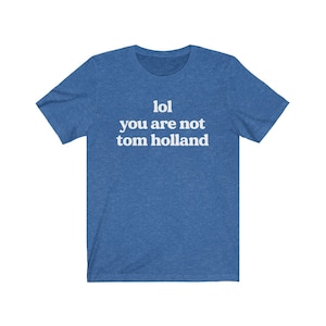 May include: A blue t-shirt with white text that reads "lol you are not tom holland".