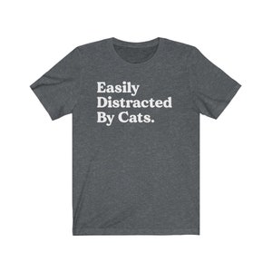Może przedstawiać: Szary t-shirt w ciemnym melanżu z nadrukiem "Easily Distracted By Cats." w kolorze białym.