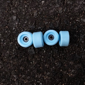 Puede incluir: Cuatro ruedas de monopatín de color azul claro con rodamientos negros.