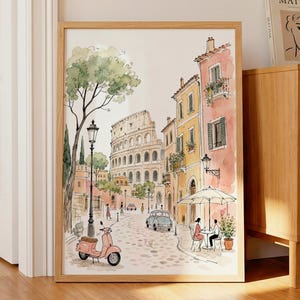 Puede incluir: Una lámina de arte en acuarela enmarcada que representa una escena callejera romana con el Coliseo al fondo, un scooter rosa en primer plano, edificios amarillos y color melocotón, una calle empedrada y dos personas en una mesa de café.