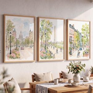 Peut inclure: Trois impressions aquarelles encadrées représentant des scènes urbaines. L'impression de gauche montre le Capitole des États-Unis, celle du centre le Washington Monument, et celle de droite des maisons colorées avec des arbres.