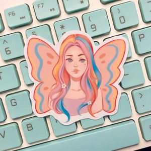 May include: A sticker featuring a colorful illustration of a person with butterfly wings. The person has long, pink, blue, and yellow hair and is wearing a light pink shirt. The butterfly wings are pink, blue, and yellow.