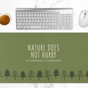 May include: Green mousepad with the text "Nature does not hurry, yet everything is accomplished" in white. A row of stylized green trees are at the bottom of the mousepad.