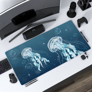 Pode incluir: Um tapete de mesa azul e branco com um design de duas medusas. As medusas são translúcidas e têm tentáculos longos e flutuantes. O fundo é azul escuro com estrelas brancas e bolhas.