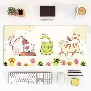 Pode incluir: Um tapete de mesa de cor verde claro, amarelo e rosa com um design de gato de desenho animado. O tapete apresenta três gatos com as palavras "Eat", "Sleep" e "Meow" acima deles. O tapete é decorado com pegadas.