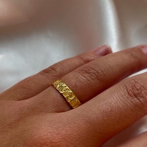 Pu&ograve; includere: Un anello a fascia d'oro con una superficie testurizzata.