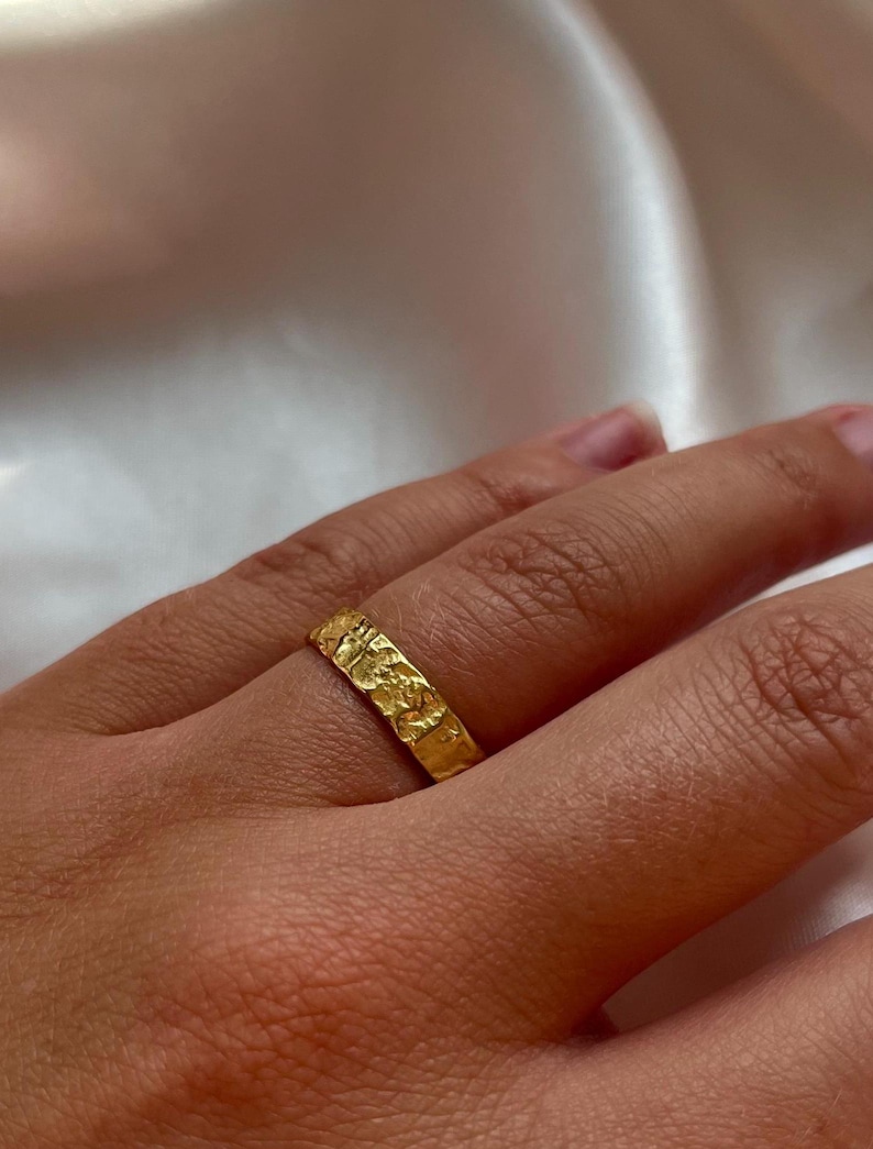 Pu&ograve; includere: Un anello a fascia d'oro con una superficie testurizzata.