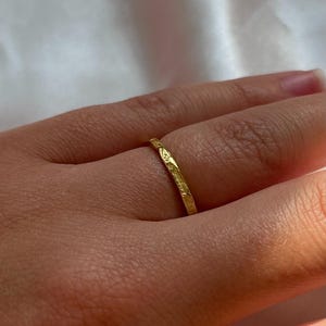 Pu&ograve; includere: Un sottile anello a fascia d'oro con una superficie testurizzata.
