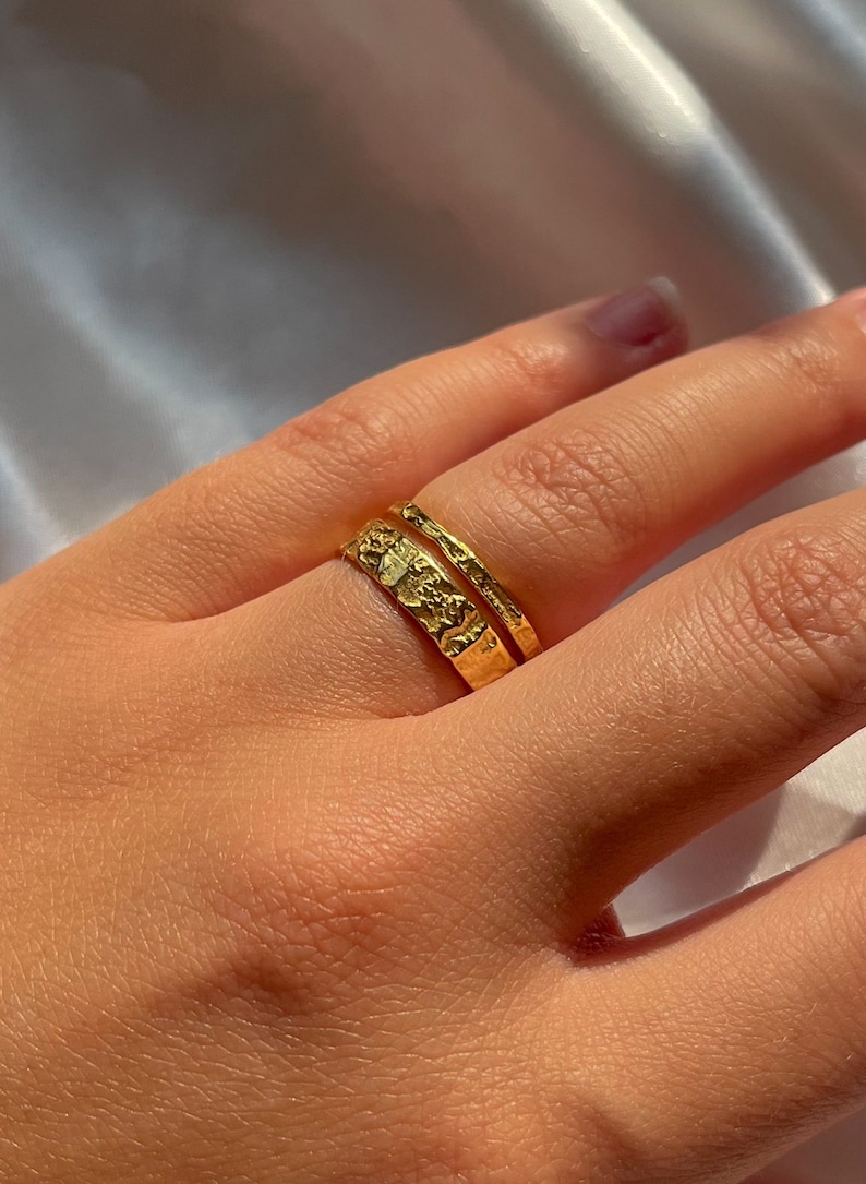 Pu&ograve; includere: Due anelli d'oro impilati su un dito. L'anello superiore &egrave; una semplice fascia, mentre l'anello inferiore ha un design testurizzato.