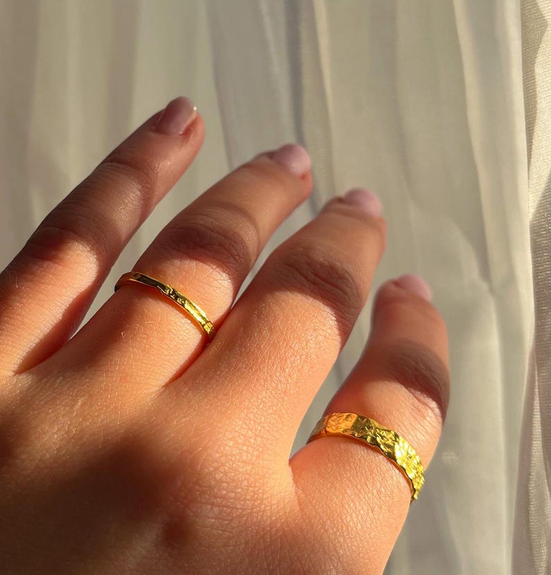 Pu&ograve; includere: Due anelli d'oro su una mano. Un anello &egrave; una fascia sottile, l'altro &egrave; una fascia pi&ugrave; spessa con una superficie testurizzata.