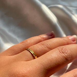 Pu&ograve; includere: Un sottile anello a fascia d'oro con una superficie testurizzata.