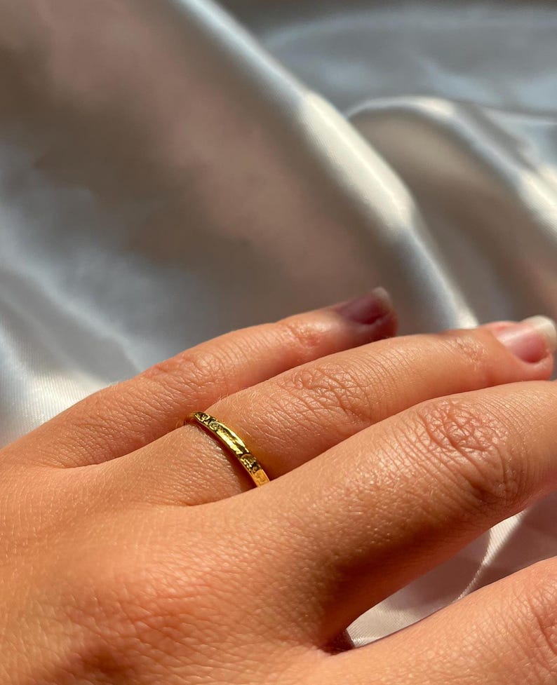 Pu&ograve; includere: Un sottile anello a fascia d'oro con una superficie testurizzata.